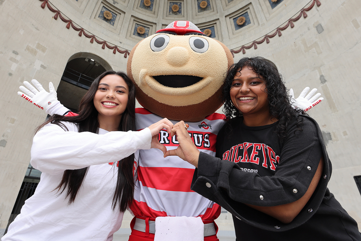 Two female students posing with Brutus Buckeye outside Ohio Stadium