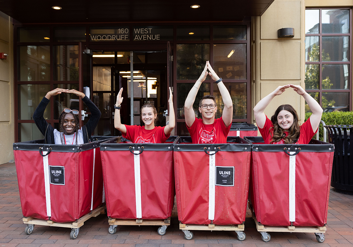 Tinu Ijewemen, Peyton Wurth, Ted Davis and Emma Salle in red bins spelling out O-H-I-O in front of Scott Hall