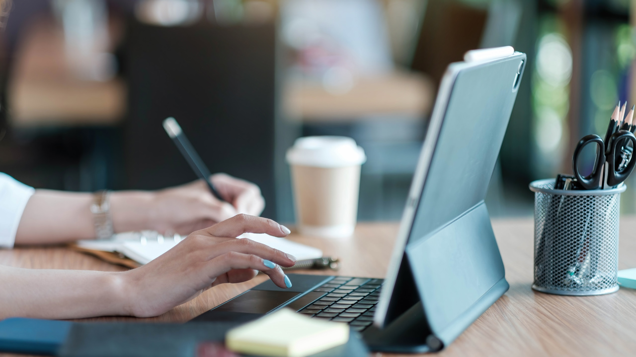 person typing into a laptop while holder a pencil