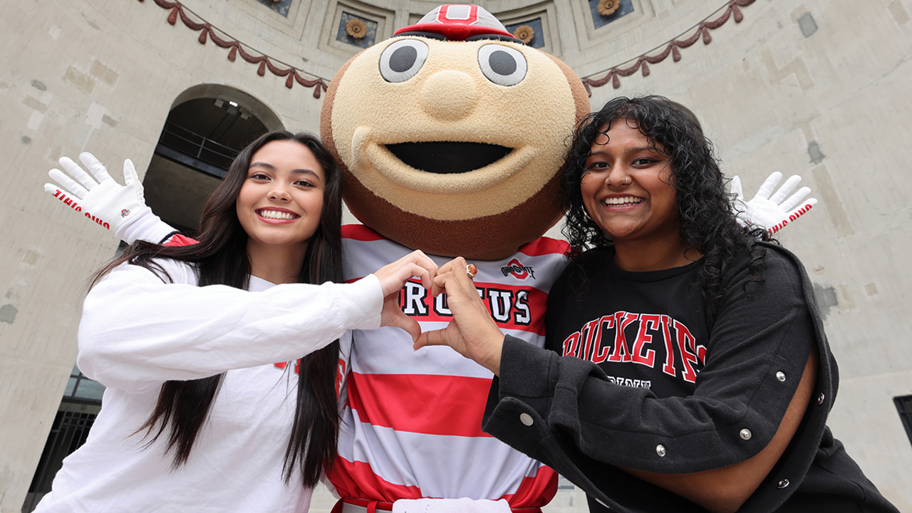 Two female students posing with Brutus Buckeye outside Ohio Stadium