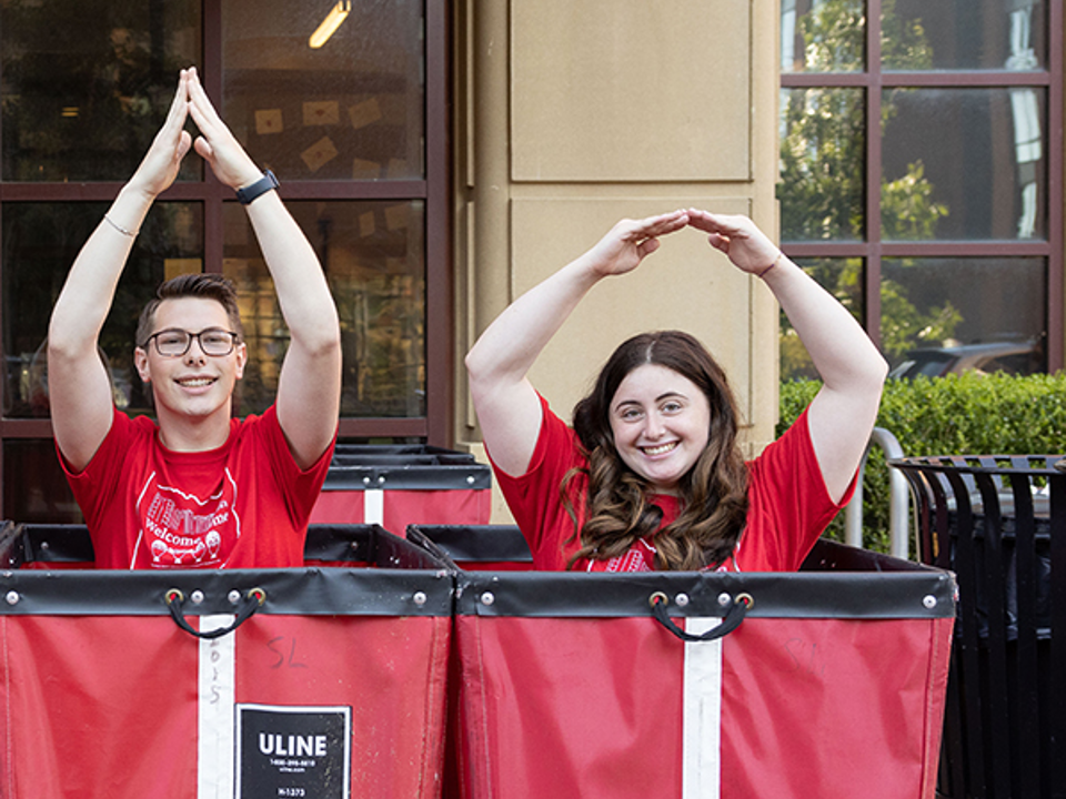 Ted Davis and Emma Salle in red bins spelling out O-H-I-O in front of Scott Hall